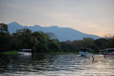 Mombacho volkanik arka plandaki göldeki feribot istasyonu. Gün batımı zamanı.