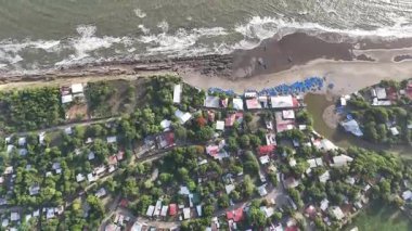 Gündüzleri açık hava aktivitelerine katılan evler, yeşil alanlar ve plaja gidenlerin yer aldığı canlı kıyı toplumunu görüntüleyin.
