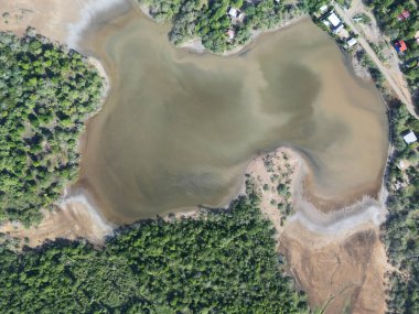 Geniş hava perspektifi, berrak gökyüzünün altındaki yeşil bitki örtüsünün arasından kıvrılarak huzurlu bir ortam yarattığını gösteriyor..