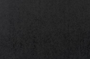 Pürüzsüz, karanlık yüzey ince dokular gösterir, muhtemelen taş ya da kumaşa benzer, yumuşak ışıklandırmayla aydınlatılır..