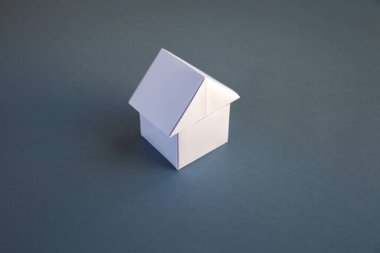 Beyaz kağıt ev origamisi boş gri bir arkaplanda izole edildi.