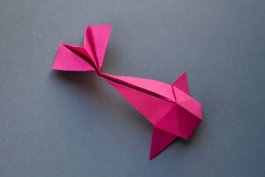 Pink paper fish origami isolated on a blank grey background