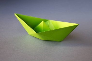 Yeşil kağıt tekne origamisi boş gri bir arkaplanda izole edildi.