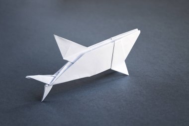 Beyaz kağıt köpek balığı origamisi gri bir arkaplanda izole edilmiş.