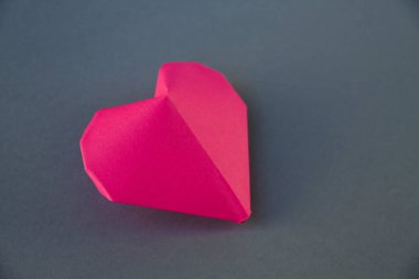 Pembe kağıt kalp origamisi gri bir arkaplanda izole edilmiş. Sevgililer Günü kartı