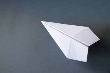 Beyaz kağıt uçak origamisi boş gri bir arkaplanda izole edildi