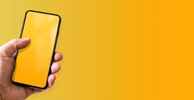 Elinde boş sarı ekranlı bir akıllı telefon var. Renkli bir geçmiş. Yatay Pankart.