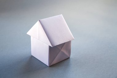Beyaz kağıt ev origamisi boş gri bir arkaplanda izole edildi.