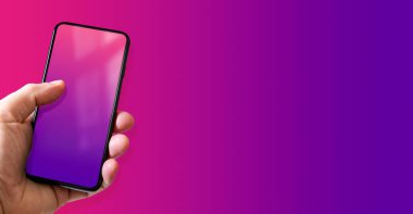 Elinde pembe ve mor ekranlı bir akıllı telefon var. Renkli bir geçmiş. Yatay Pankart.