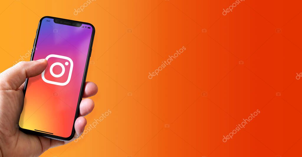 Paris - France - March 15, 2022 : Hand holding iphone smartphone with Instagram logo. Horizontal banner