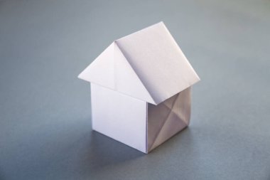 Beyaz kağıt ev origamisi boş gri bir arkaplanda izole edildi.