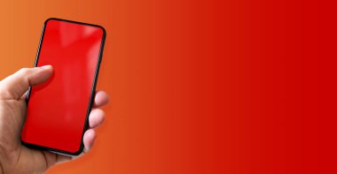 Elinde boş kırmızı ekranlı bir akıllı telefon var. Renkli bir geçmiş. Yatay Pankart.