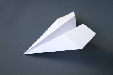Beyaz kağıt uçak origamisi boş gri bir arkaplanda izole edildi