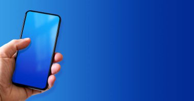 Elinde boş mavi ekranlı bir akıllı telefon var. Renkli bir geçmiş. Yatay Pankart.