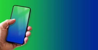 Elinde boş mavi ve yeşil ekranlı bir akıllı telefon var. Renkli bir geçmiş. Yatay Pankart.