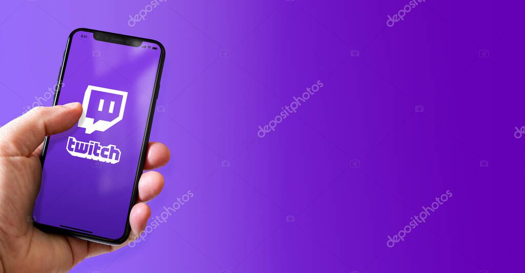 Paris - France - March 15, 2022 : Hand holding iphone smartphone with Twitch logo. Horizontal banner