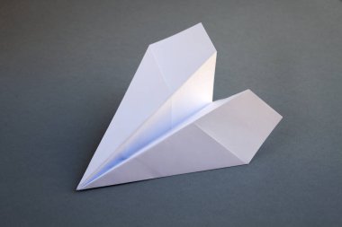 Beyaz kağıt uçak origamisi boş gri bir arkaplanda izole edildi