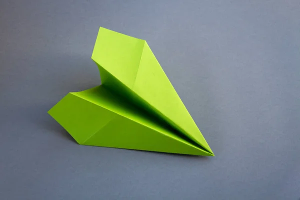 Green paper plane origami isolated on a blank grey background