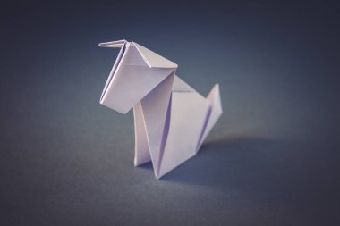 Beyaz kağıt köpek origamisi boş gri bir arkaplanda izole edildi.