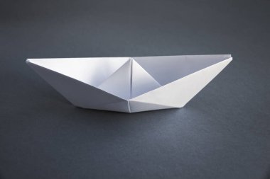 Beyaz kağıttan origami gri bir arkaplanda izole edilmiş..