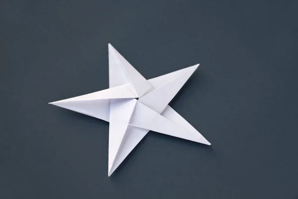 White paper star origami isolated on a blank grey background.