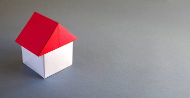 White and red paper house origami isolated on a grey background.