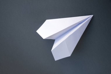 Beyaz kağıt uçak origamisi boş gri bir arkaplanda izole edildi