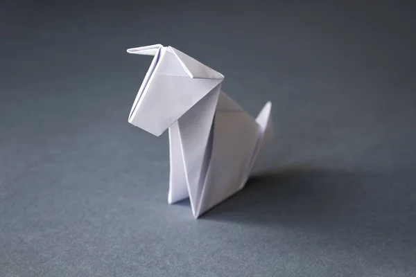 White paper dog origami isolated on a blank grey background.