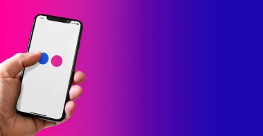 Paris - France - March 15, 2022 : Hand holding iphone smartphone with Flickr logo. Horizontal banner