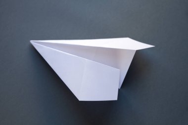 Beyaz kağıt uçak origamisi boş gri bir arkaplanda izole edildi