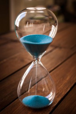 Kırsal ahşap arka planda mavi kum içeren kum saati.