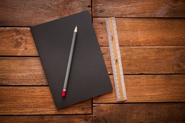 Kapalı defter, kalem ve kırsal bir tahta üzerinde eski model cetvel.