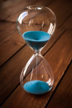 Kırsal ahşap arka planda mavi kum içeren kum saati.