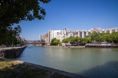 Paris - France - June 05, 2023 : Ourcq canal and houseboat view from the banks in summer clipart