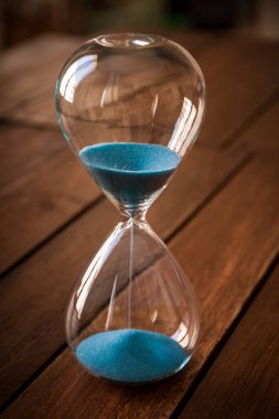 Kırsal ahşap arka planda mavi kum içeren kum saati.