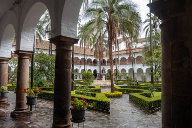 Quito, Ekvador 'daki tarihi San Francisco manastırı ve kilise avlusunda koloni mimarisi, palmiye ağaçları ve sakin bir çeşme yer alıyor.