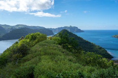 Nuku Hiva 'daki Taipivai Körfezi' nin sakin sularını çevreleyen yemyeşil tepeler. Bu uzak Markiz manzarası el değmemiş doğayla nefes kesici kıyı manzarasını harmanlıyor.