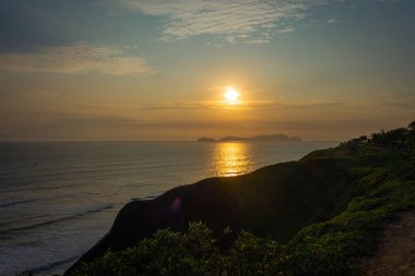 Golden Gate Sahili 'nin kumlu kıyısı Pasifik Okyanusu' yla kesişiyor. Açık mavi gökyüzünün altında San Francisco ufuk çizgisi görünüyor.
