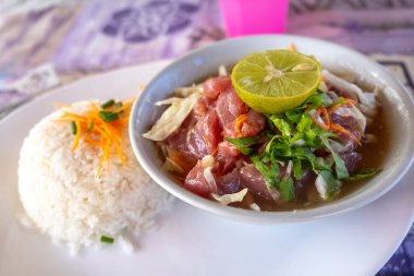 Hiva Oa 'dan geleneksel bir Polinezya çiğ balığı tabağı, Fransız Polinezyası, taze ton balığı, sebze, limon ve hindistan cevizi sütü ile birlikte beyaz bir tabakta pirinç eşliğinde.