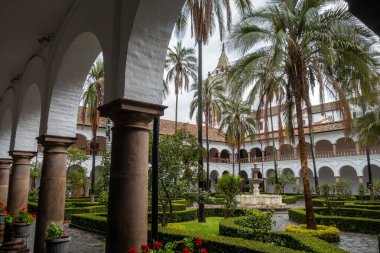 Quito, Ekvador 'daki tarihi San Francisco manastırı ve kilise avlusunda koloni mimarisi, palmiye ağaçları ve sakin bir çeşme yer alıyor.