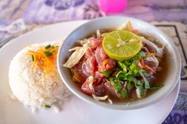 Hiva Oa 'dan geleneksel bir Polinezya çiğ balığı tabağı, Fransız Polinezyası, taze ton balığı, sebze, limon ve hindistan cevizi sütü ile birlikte beyaz bir tabakta pirinç eşliğinde.