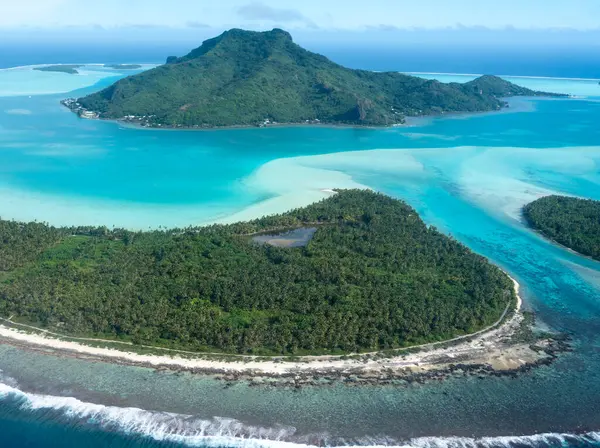 Fransız Polinezyası 'ndaki Maupiti Adası' nın çarpıcı hava manzarası turkuvaz sularını, yemyeşil suları ve adanın ikonik dağlarını vurguluyor.
