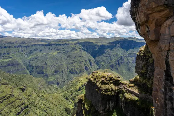 Waqrapukara arkeolojik alanını çevreleyen yeşil dağ tepeleri ve sarp kayalıklar, And 'ın berrak mavi gökyüzü altında nefes kesici panoramik manzaralar sunuyor.