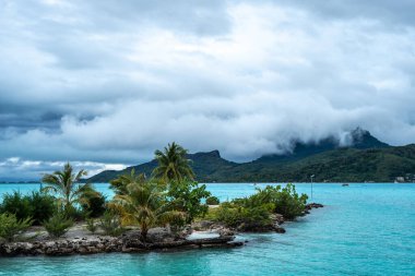 Palmiye ağaçlarıyla kaplı bir sahilden Bora Bora adasının manzarası Fransız Polinezyası 'nda mükemmel bir tropik cennet sunuyor.