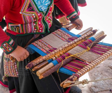 Cusco, Peru yakınlarındaki bir zanaatkar, kemer bağıyla geleneksel bir dokuma tezgahı örüyor. Titreşimli desenler And 'ın mirasını ve yerli işçiliğini yansıtıyor.