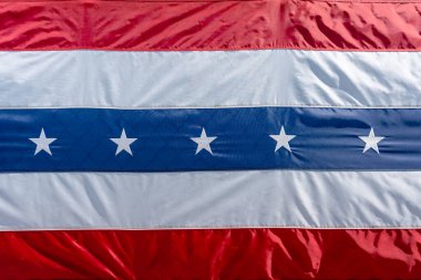 Kırmızı, beyaz ve mavi çizgili vatansever bir bayrak. Merkezi mavi bölümde Amerikan gurur ve geleneğini sembolize eden beyaz yıldızlar yer almaktadır. ABD