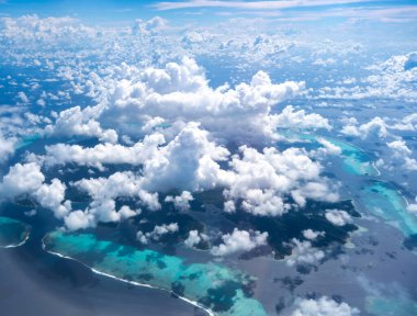 Turkuaz lagün ve mercan resifleriyle çevrili çarpıcı Tahaa adası engin Pasifik Okyanusu 'ndaki dağınık bulutların arasından çıkar. Nefes kesici bir hava bakış açısı.