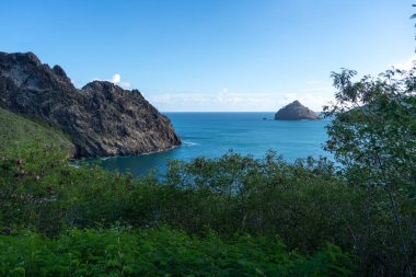 Marquesas Adaları 'ndaki Nuku Hiva' daki Taiohae Körfezi 'nin engebeli uçurumları parlak bir gökyüzünün altından çıkan küçük kayalık adalarla derin mavi Pasifik Okyanusu' na düşer. Fransız Polinezyası