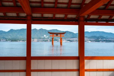 Kutsal Itsukushima Tapınağı yüzen kırmızı torii kapısıyla Japonya 'daki Miyajima adasının sakin sularına ve dağlarına bakıyor.