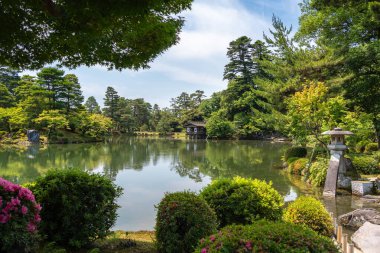 Kanazawa 'daki Kenroku-en Bahçesi gölet, taş fener ve yemyeşil bitki örtüsüyle doğal güzellik ve uyumu harmanlayarak barışçıl bir atmosfer yaratır.